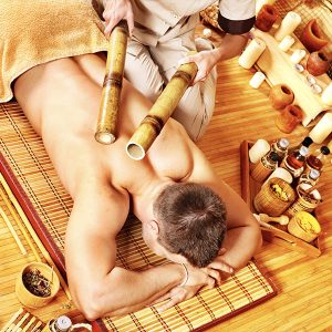 a person lying down with bamboo sticks over his back