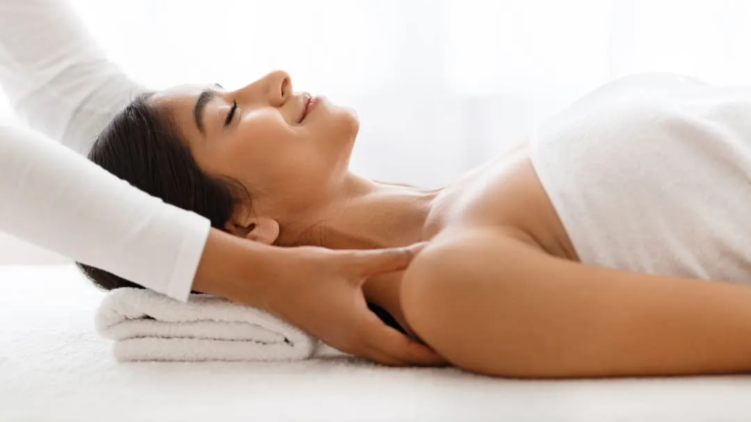 Une femme recevant un massage du dos dans un spa, utilisant la technique de polarité.